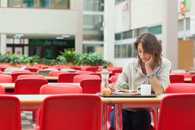 Studente triste nella mensa con vassoio di cibo