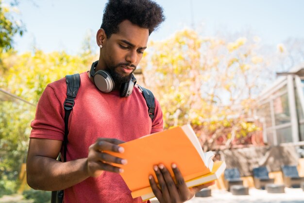 Studente universitario afro che studia e legge il suo libro