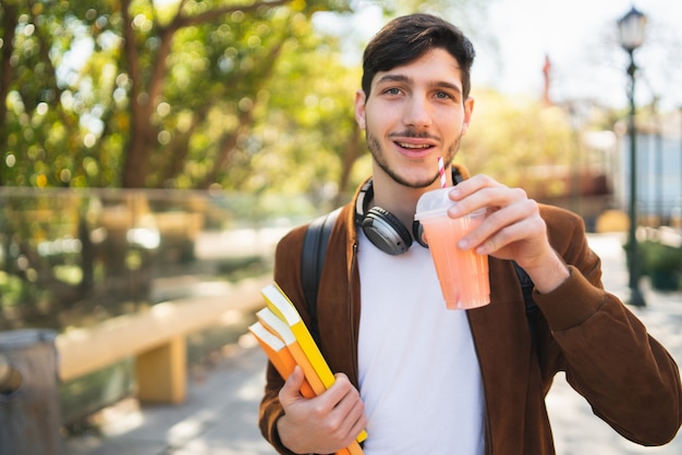 Studente universitario che cammina sulla strada mentre si tiene i suoi libri