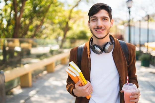 Studente universitario che cammina sulla strada mentre si tiene i suoi libri.