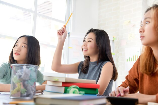 Studente universitario oltremare femminile che solleva la sua mano che fa domanda nella classe