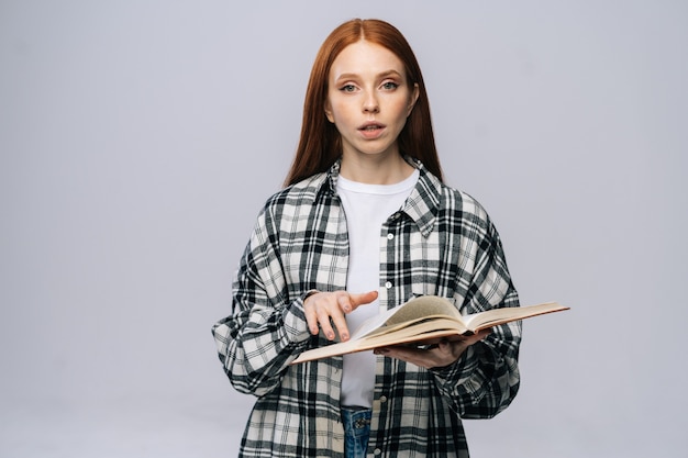 Studente universitario serio della giovane donna che gira le pagine del libro mentre legge