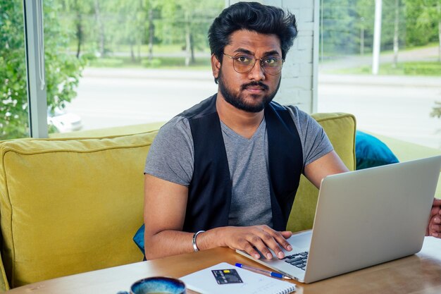 Studente uomo d'affari bello e di successo in un libero professionista elegante e ben vestito che lavora con un laptop. freelance e lavoro a distanza.