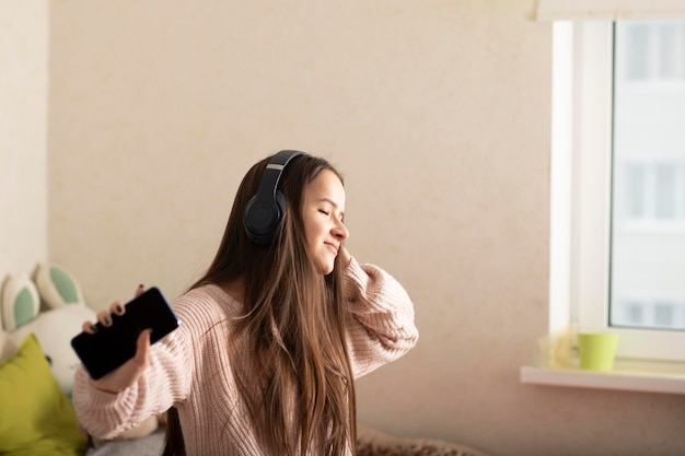 Studentessa adolescente e millennial che balla nella sua stanza con le cuffie