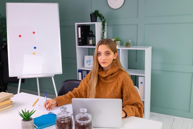 Studentessa adolescente sorridente felice che guarda l'apprendimento online video zoom classe webinar in classe virtuale sul suo laptop. Formazione online a distanza, concetto di studio da casa.