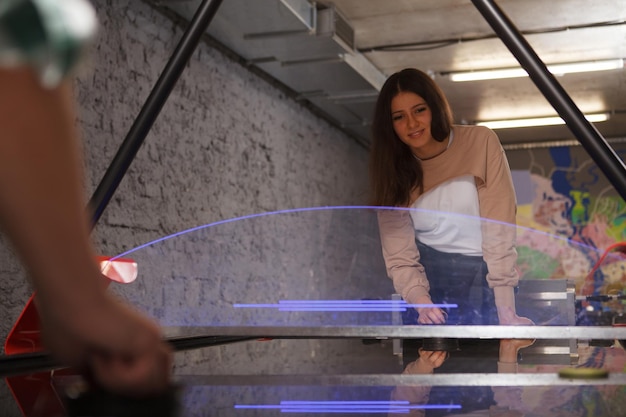 Studentessa adorabile che si diverte a giocare a air hockey nella sala ricreativa del campus universitario