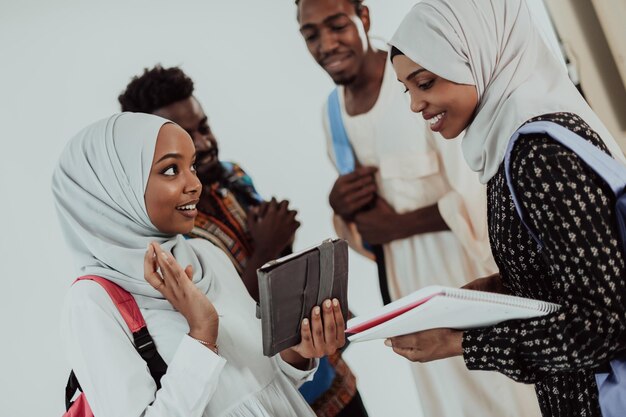 Studentessa africana con un gruppo di amici sullo sfondo che indossano abiti tradizionali hijab islamici. Messa a fuoco selettiva. Foto di alta qualità