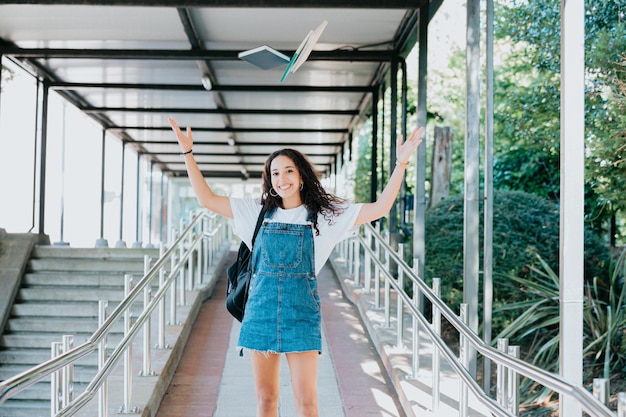 Studentessa africana in piedi all'aperto in possesso di libri universitari. Ritratto di giovane donna africana che guarda l'obbiettivo, concetto di istruzione. La giovane donna dalla pelle scura felice ottimista getta i libri in aria