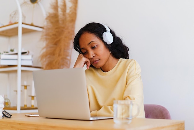 Studentessa afroamericana annoiata e stanca che guarda la lezione a distanza online sul laptop