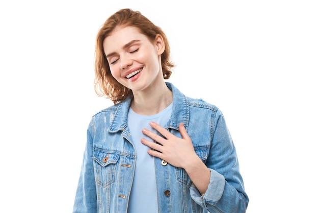 studentessa amichevole in giacca di jeans sorriso affascinante che tiene per mano il cuore amore sfondo bianco