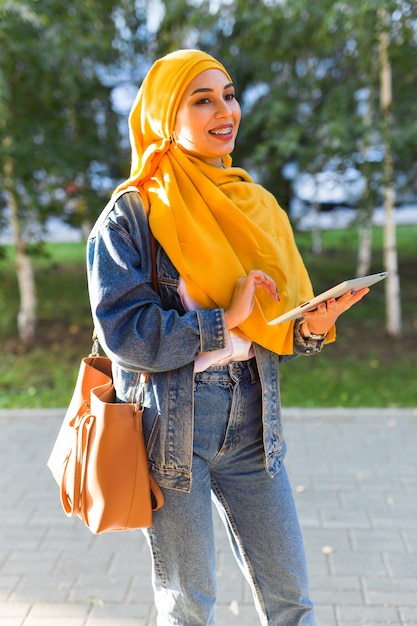 Studentessa araba. Bella studentessa musulmana che indossa il tablet hijab giallo brillante.