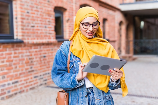 Studentessa araba. Bella studentessa musulmana che indossa il tablet hijab giallo brillante.