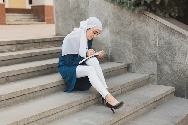 Studentessa araba seduta sulle scale nel centro cittadino
