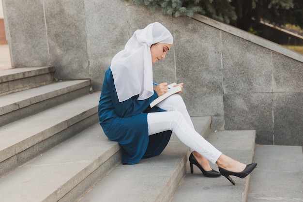 Studentessa araba seduta sulle scale nel centro cittadino