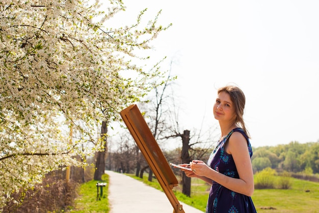 Studentessa artista pittura paesaggio all'aria aperta all'inizio della primavera