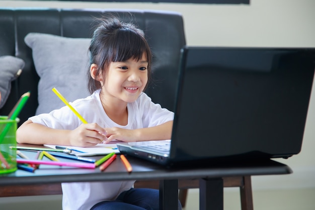 studentessa asiatica che studia i compiti durante la sua lezione online a casa