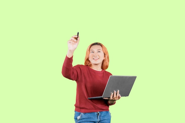 Studentessa asiatica dell'adolescente che disegna nell'aria o sullo schermo immaginario mentre tiene un computer portatile
