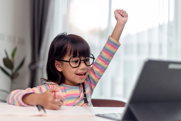 Studentessa asiatica in classe di apprendimento online studia online con l'insegnante La ragazza felice impara la lingua inglese online con il tablet a casa Nuova normalitàCovid19 coronavirusDistanziamento sociale resta a casa