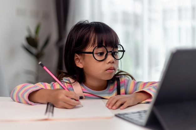 Studentessa asiatica in classe di apprendimento online studia online con l'insegnante La ragazza felice impara la lingua inglese online con il tablet a casa Nuova normalitàCovid19 coronavirusDistanziamento sociale resta a casa