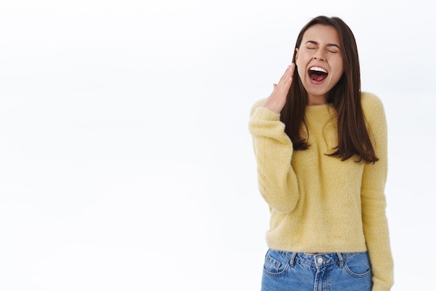 Studentessa assonnata carina sciocca bruna annoiata frequenta una lezione noiosa sbadigliando con la bocca aperta coprirla con il palmo come occhi chiusi e allungandosi stanca al mattino presto ha bisogno di caffè sfondo bianco