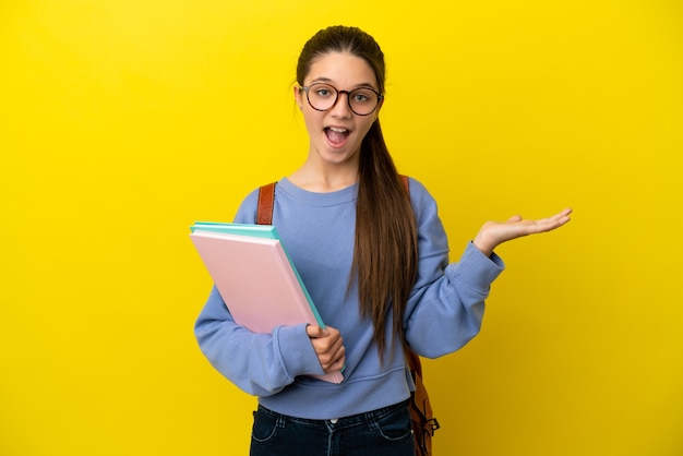 Studentessa bambino donna su sfondo giallo isolato con espressione facciale scioccata