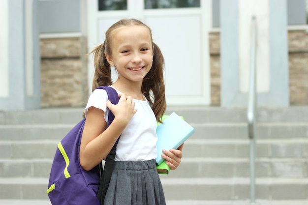 Studentessa carina con uno zaino scolastico nel cortile della scuola