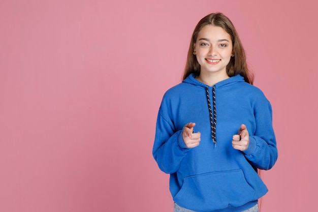 Studentessa carina sicura che punta alla telecamera con entrambe le mani mentre sorride ampiamente alla telecamera