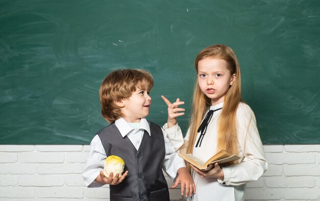 Studentessa che aiuta gli alunni che studiano ai banchi in classe Insegnante e bambino Sfondo lavagna Bambini piccoli a lezione di scuola Bambini della scuola primaria Processo educativo