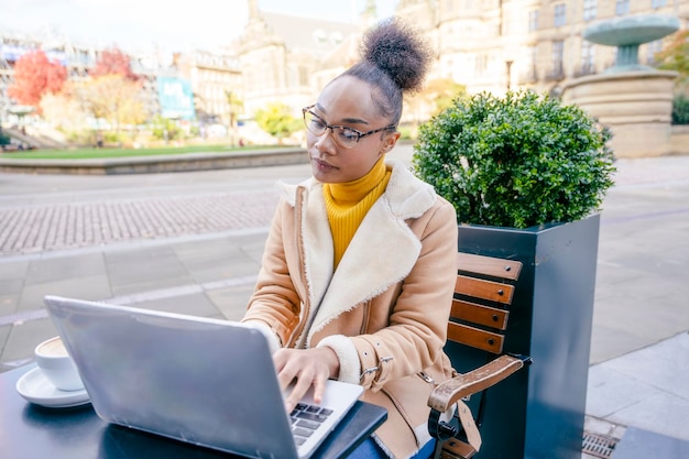 Studentessa che impara lavorando al caffè guardando il webinar di formazione online utilizzando un computer portatile