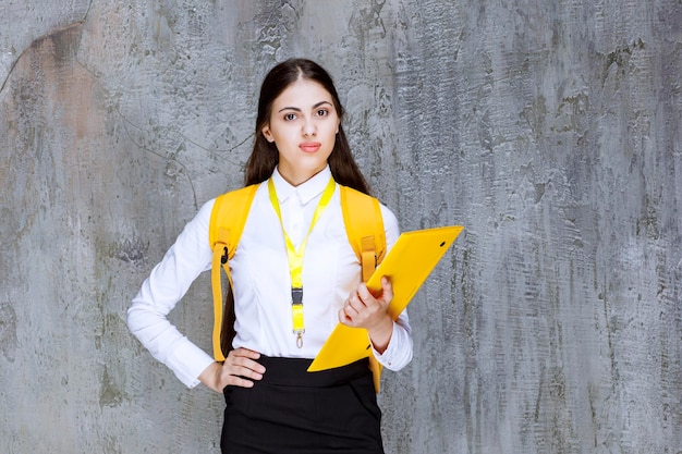 Studentessa che indossa il blocco note della tenuta dello zaino giallo. Foto di alta qualità