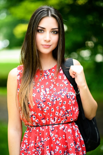 Studentessa che tiene passeggiate all'aperto nel parco e sorridente