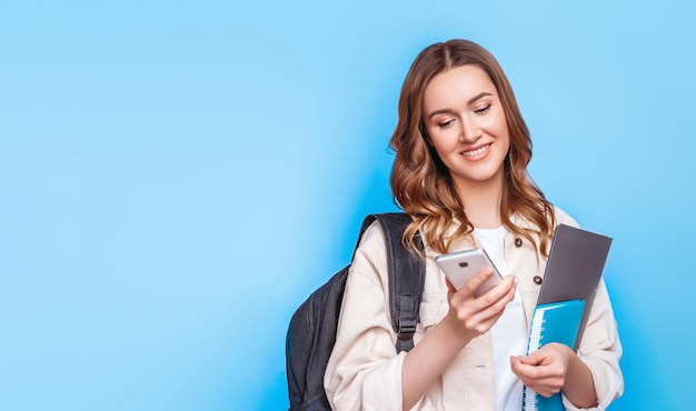 Studentessa che utilizza lo smartphone per digitare messaggi isolati su banner web di sfondo blu