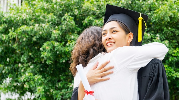 Studentessa con gli abiti di laurea e cappello abbraccia il genitore nella cerimonia di congratulazioni.