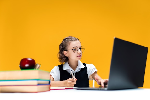 Studentessa con gli occhiali che scrive e guarda il laptop durante la lezione online apprendimento scolastico a distanza