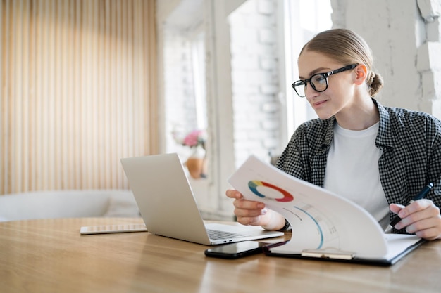 Studentessa con occhiali sul posto di lavoro in ufficio utilizza il computer portatile