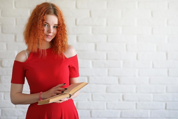 Studentessa dai capelli rossi su uno sfondo di muro di mattoni