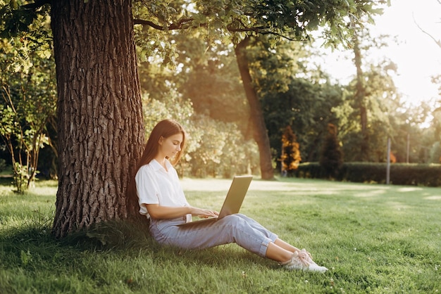 Studentessa della giovane donna con il computer portatile nel parco