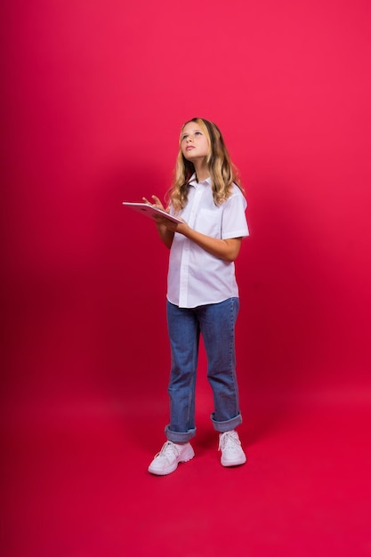 Studentessa di app della scuola online che mostra lo schermo vuoto del computer tablet su sfondo rosso girato in studio