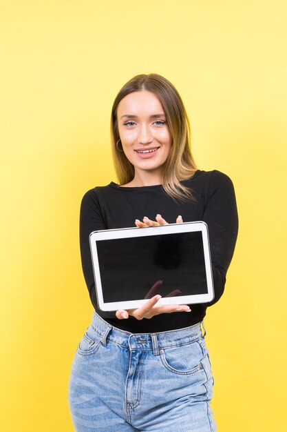 Studentessa giovane donna caucasica intelligente intelligente utilizzando tablet digitale isolato su sfondo giallo