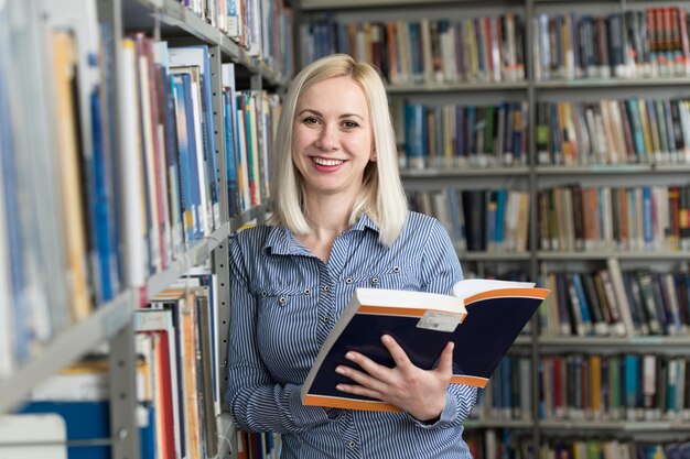 Studentessa graziosa con libri che lavorano in una biblioteca del liceo