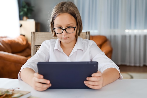 Studentessa impegnata in homeschooling guardando la lezione di apprendimento online sul laptop a casa Bambino che frequenta una classe di scuola virtuale remota ascoltando l'insegnante Apprendimento remoto a casa con la tecnologia