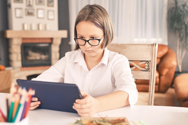 Studentessa impegnata in homeschooling guardando la lezione di apprendimento online sul laptop a casa Bambino che frequenta una classe di scuola virtuale remota ascoltando l'insegnante Apprendimento remoto a casa con la tecnologia