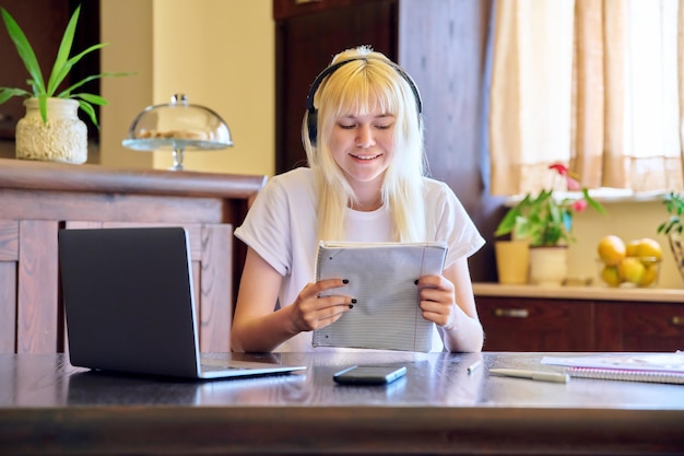 Studentessa in cuffia utilizzando un computer portatile che studia a casa