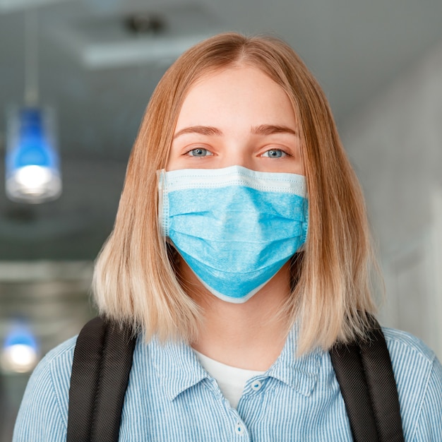 Studentessa in maschera protettiva blu con zaino. Giovane studentessa in maschera medica all'università