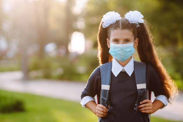 Studentessa in maschera sterile protettiva quando torna a scuola durante la quarantena COVID19