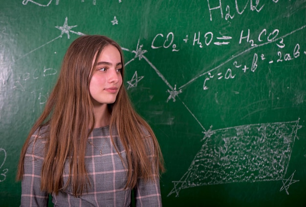 Studentessa in piedi vicino a una lavagna pulita in classe