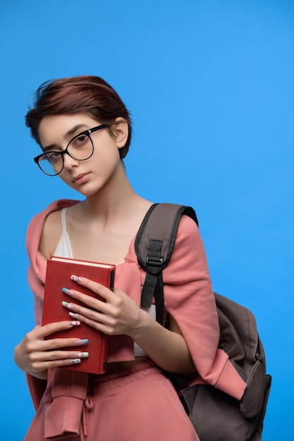 Studentessa in vetri con libro e zaino