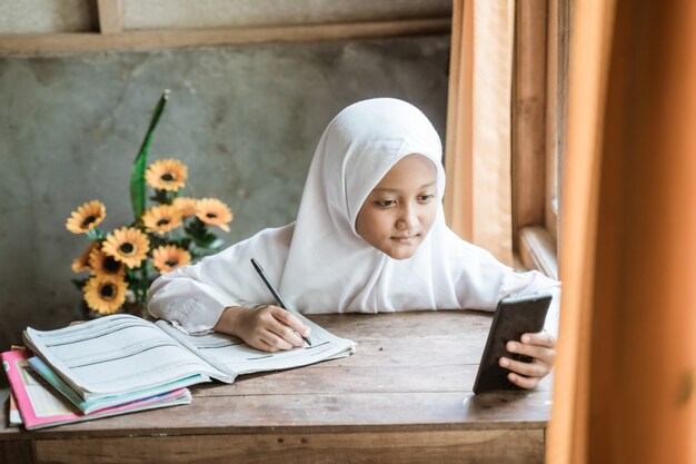 Studentessa indonesiana che studia i compiti durante la lezione online a casa