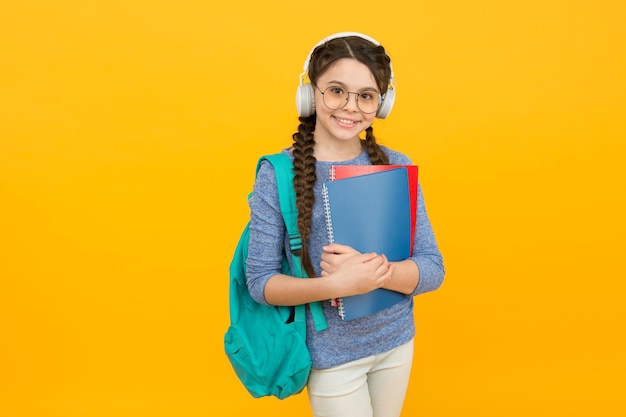 Studentessa moderna con zaino e forniture scolastiche sfondo giallo homeschooling concetto