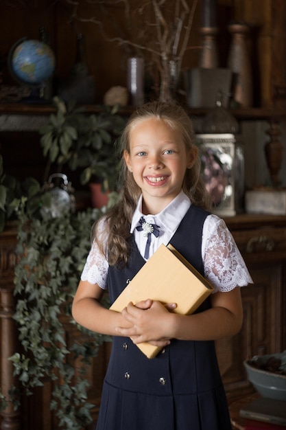 Studentessa primaria in uniforme scolastica con un libro